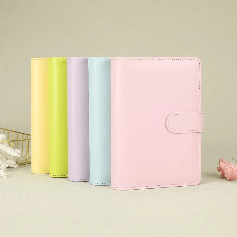 Agenda A5 rosa sobre fondo de escritorio con accesorios de papelería.