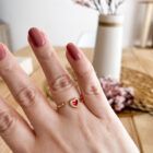 Anillo corazón rojo con circonitas, lucido en mano femenina.