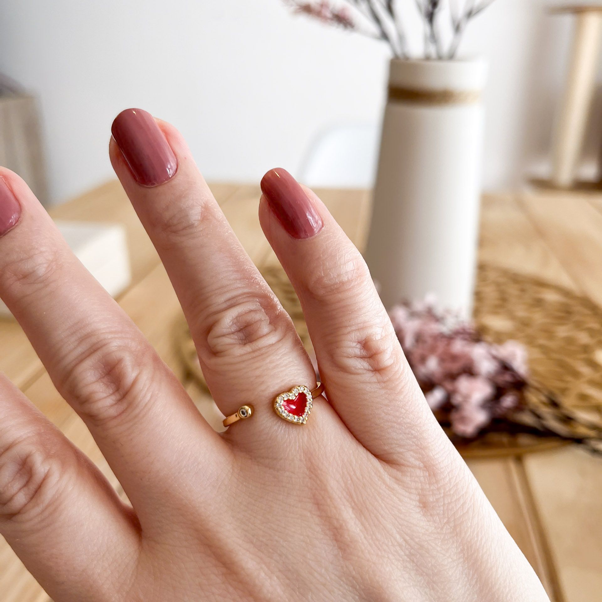 Anillo corazón rojo con circonitas, lucido en mano femenina.