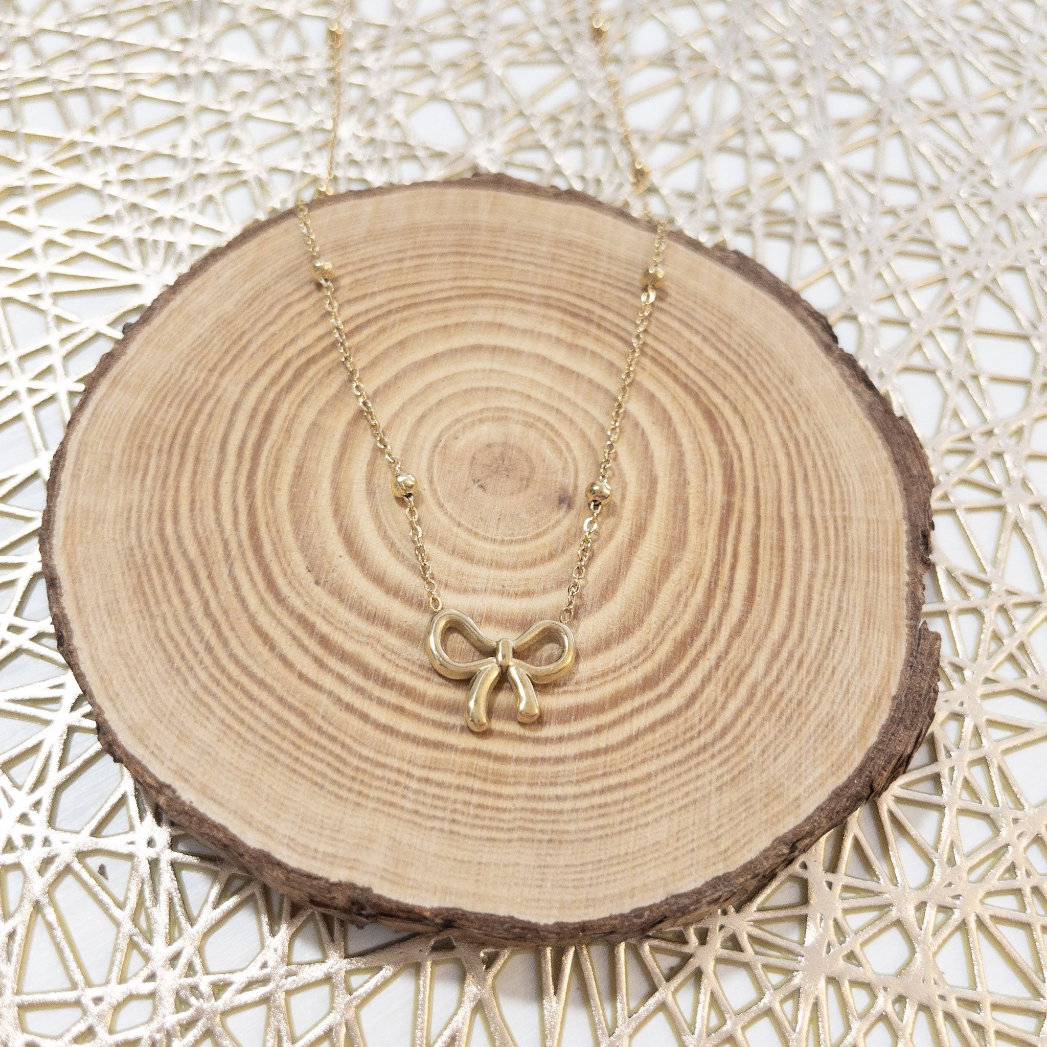 Collar dorado con lazo sobre madera